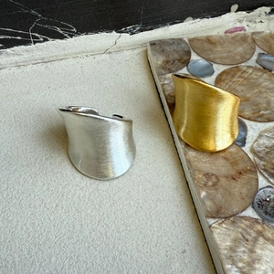 Detail of minimalist irregular wide open rings in gold and silver with brushed texture