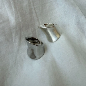 Close-up of minimalist silver irregular wide rings with polished and brushed finishes