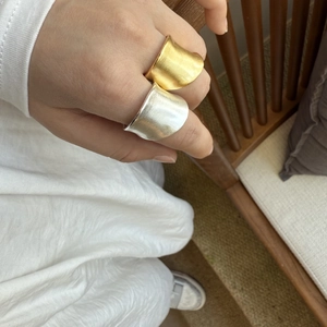 Detail view of irregular brushed metal wide rings in gold and silver matte finishes