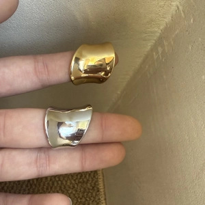 Detail of wavy gold and silver wide band rings with a polished mirror finish on hand