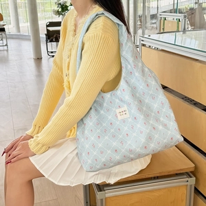 Detail of light blue floral knit tote bag showing tulip pattern and shoulder strap texture
