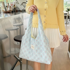 Close-up of floral print blue tote bag with quilted pattern and brand woven label