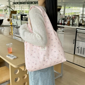 Close-up of pink floral fabric tote bag with elegant logo label and soft texture