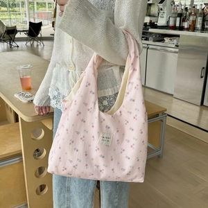 Detailed view of pink floral canvas tote bag featuring a stitched brand logo label