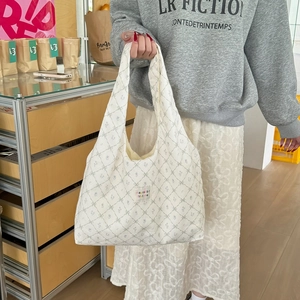 Close-up of floral print canvas tote bag with embroidered logo patch and vintage pattern