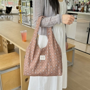Detail of floral print fabric tote bag with woven label in a cozy cafe setting