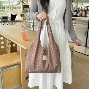 Close-up of brown floral canvas tote bag with blue patterns and branded fabric label