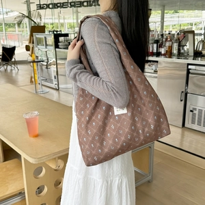 Detail of floral plaid shoulder bag featuring blue patterns and white brand label tag