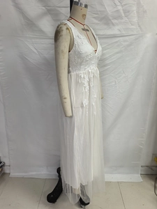 Detail of white lace dress featuring intricate floral embroidery and deep V-neckline