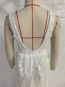 Detail of white lace embroidered gown featuring a deep V-back and hidden zipper closure