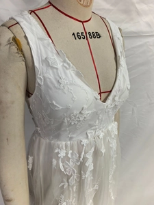 Close-up of elegant 3D floral embroidery and hollow lace detail on a white V-neck dress