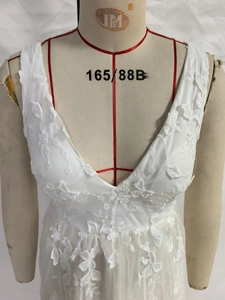 Close-up of white lace dress featuring intricate floral embroidery and deep V-neck detail