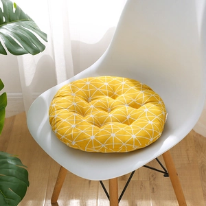 Comfortable round yellow chair cushion with white geometric pattern on a white chair