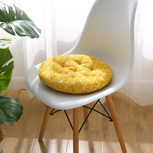 Yellow round chair cushion with white geometric grid pattern and tufted design
