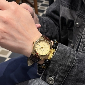 Detail of men's gold quartz watch with brown leather strap and black beaded bracelet