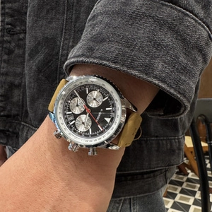 Close-up of men's chronograph watch with black dial and tan leather strap on wrist