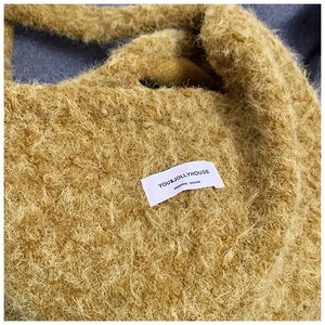 Close-up of yellow fuzzy plush tote bag showing soft curly texture and brand label