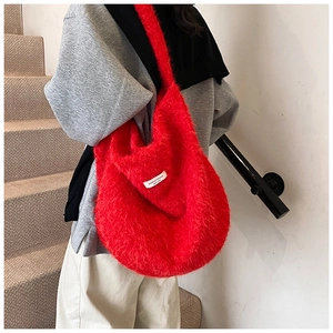Macro view of plush red faux fur texture and white label on large shoulder tote bag