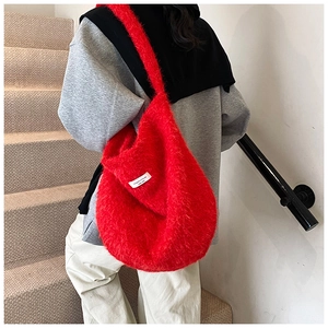 Detail of red plush hobo bag with soft faux fur texture and white woven brand label