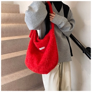 Detail of red plush tote bag showing soft faux fur texture and branded woven label
