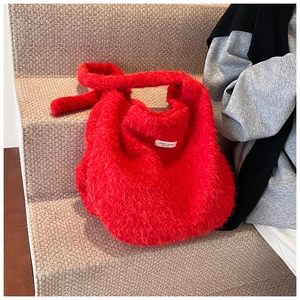 Detailed close-up of fluffy red plush tote bag with decorative knot and white logo patch