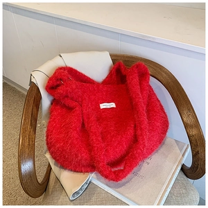 Detail of soft red faux fur tote bag showing plush texture and white square brand label