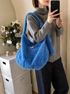 Klein blue fuzzy plush hobo bag with wide shoulder strap in a cozy winter setting