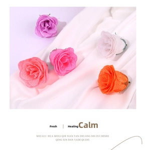 Close-up of glitter-coated artificial rose heads in assorted pastel colors on white fabric