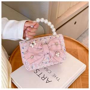 Detail of pink tweed mini handbag with large pearl handle and oversized bow decoration