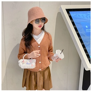 Detail of girl's orange knit cardigan with pearl strap bag and brown pleated skirt outfit