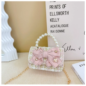 Detail of pink tweed girl's mini bag with pearl handle and satin bow decoration