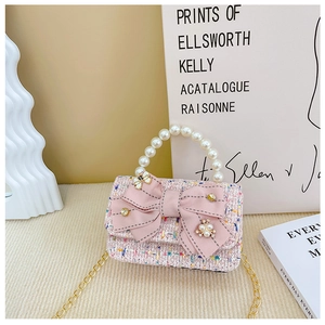 Detail of pink tweed girl handbag with large bow, pearl handle and metal chain strap