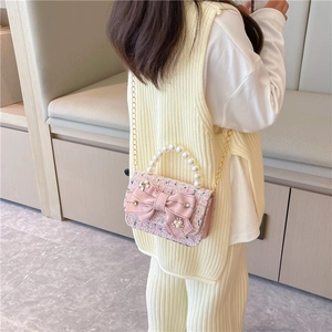Pink tweed girls' crossbody bag with pearl handle and large bow displayed on a model
