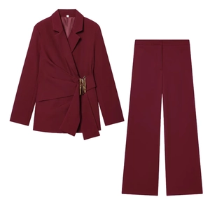 Detail of burgundy wrap blazer featuring a polished gold buckle and draped side pleats