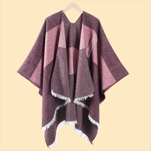 Detail eines mehrfarbigen Strickponchos mit weißen Fransen und weicher Textur