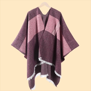 Detail eines Strickponchos mit Blockfarben in Lila und Burgund sowie weißen Fransen