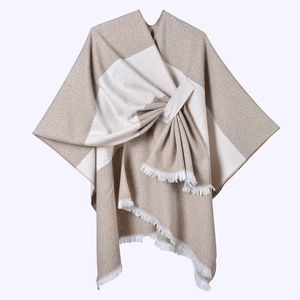 Close-up of beige and white plaid knit shawl featuring delicate fringe and wrap-style detail