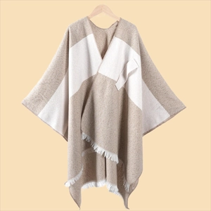 Detailansicht des Strickponchos mit Farbblock-Design, weißen Fransen und weicher Textur