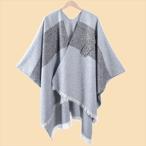 Detailansicht grauer Strickponcho mit Kontraststreifen, Tasche und weißen Fransen