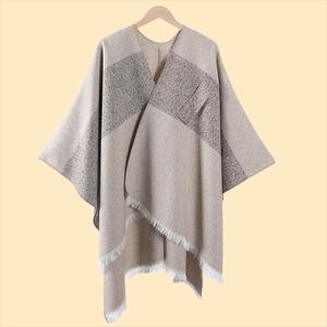 Detail der Strickstruktur und Fransen an einem beige-braunen Poncho in Kaschmir-Optik