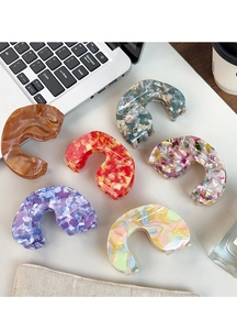 Macro view of six acetate hair claws in various marble patterns on an office desk