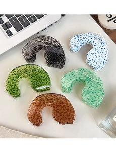 Detail of five assorted leopard print and patterned acetate hair claws on a white desk