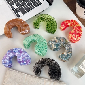 Set of seven elegant acetate hair claws in various marble and floral textures on a white desk
