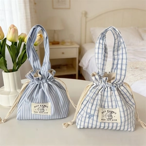 Détail des sacs à cordon à rayures et carreaux bleus avec broderies de nœuds mignons