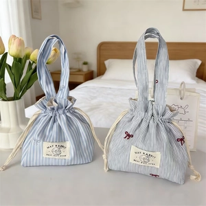 Détail de sacs en toile rayée bleue avec imprimés lapins mignons et broderie de nœuds