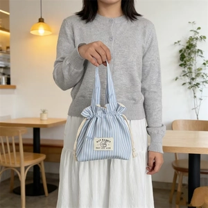 Détail du sac à cordon en toile rayée bleue avec broderie lapin et anses en coton doux