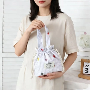 Détail du sac seau en toile rayée avec broderies de fleurs et cordon de serrage doux