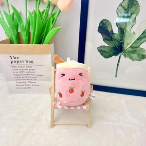 Close-up of strawberry plush milk tea cup toy with CE label on a miniature wooden chair