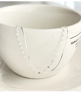 Close-up of minimalist double-layer 925 silver snake chain bracelet on white ceramic