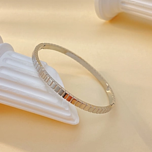 Macro shot of a modern silver bangle with vertical striped geometric cube texture on a pillar